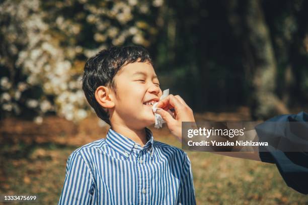 a boy having his mother wipe his mouth. - geschwister frech stock-fotos und bilder