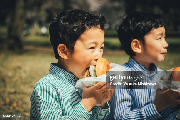 brothers eating food outdoors. - adults eating hamburgers stock-fotos und bilder
