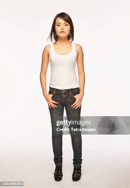 studio portrait of woman in white tank top - skinny jeans on white stock pictures, royalty-free photos & images