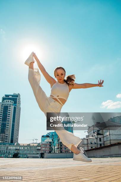 professional gymnast girl dancer jumping outdoor in city - turner contemporary stock-fotos und bilder