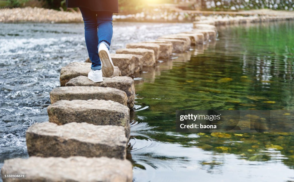 Mujer cruzando un río en escalones