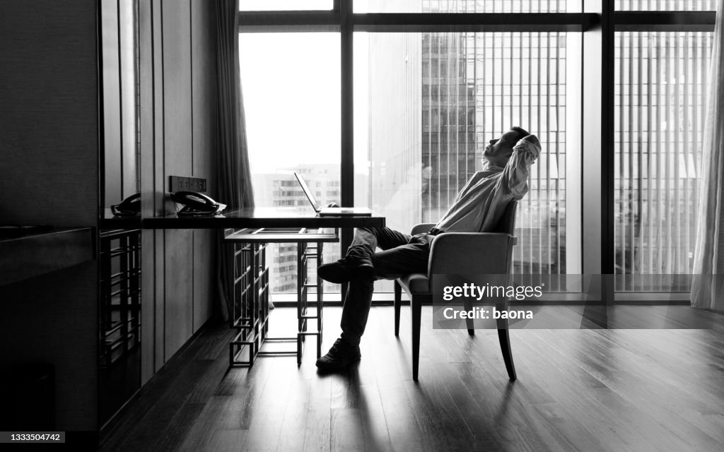 Businessman leaning on chair with hands behind head