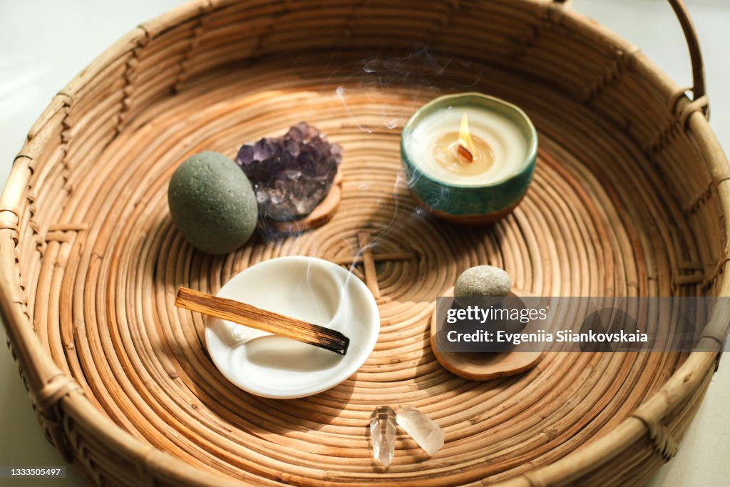 Stick of aromatic tree Palo Santo for meditation with different stones, minerals and candle in a plate.