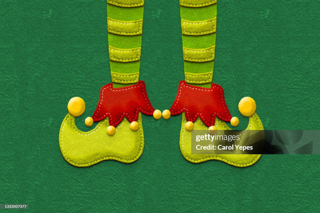 Elf feet made of felt in green background with copyspace