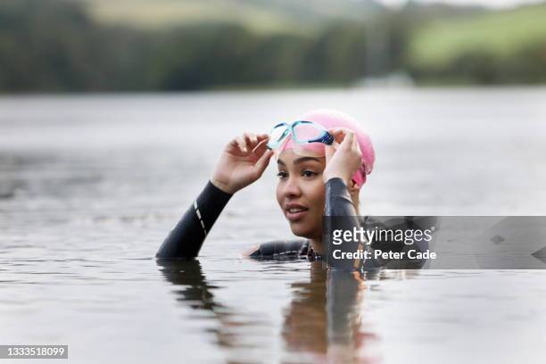 woman swimming in lake wearing wetsuit - sea swimming stock pictures, royalty-free photos & images