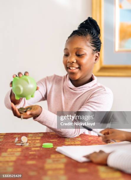 smiling young girl and her friend emptying their piggy bank - allowance bildbanksfoton och bilder