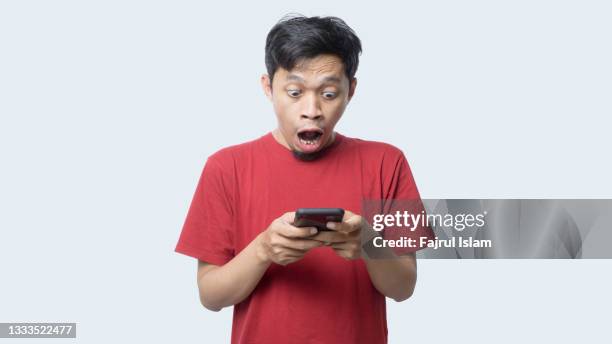 asian man shocking looking at smartphone - サプライズ ストックフォトと画像