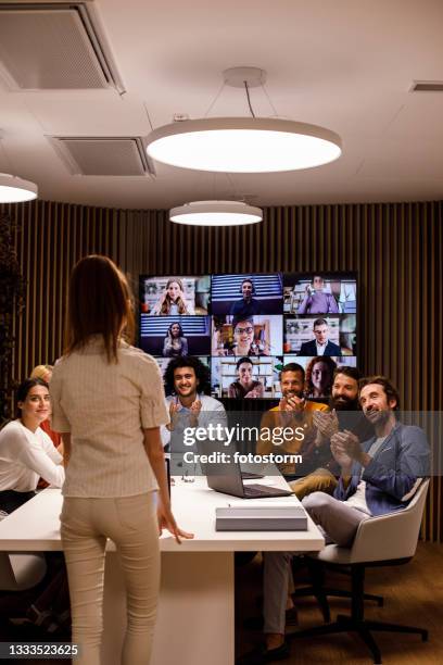 business people applauding their female colleague on a successful presentation - young businessman using a virtual screen stockfoto's en -beelden