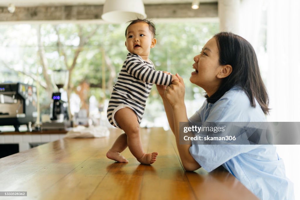 Candid shot happiness and togetherness Asian mother supporting daughter try to standing and walking first time and positive emotion