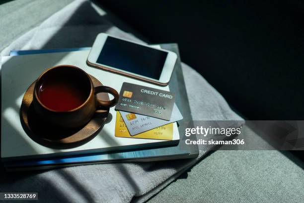 wooden cup of coffee and books  with credit card and phone on the cozy sofa - reading glasses on table stock pictures, royalty-free photos & images