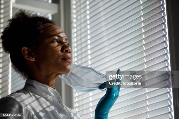 copy space shot of female doctor taking off her surgical mask - removing surgical mask stock pictures, royalty-free photos & images