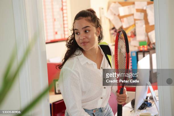 Woman leaving office with tennis equipment