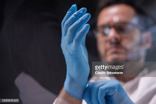 low angle view of scientist putting on surgical gloves - surgical glove stock pictures, royalty-free photos & images