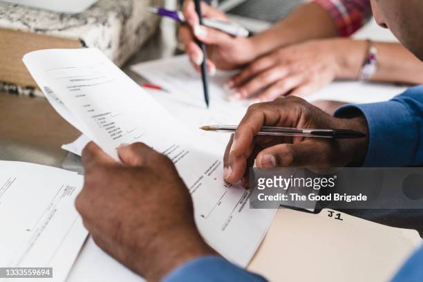close up of couple filling out paperwork at home - manilla folder stock pictures, royalty-free photos & images