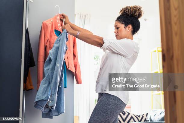 woman organizing closet at home - top capo di vestiario foto e immagini stock