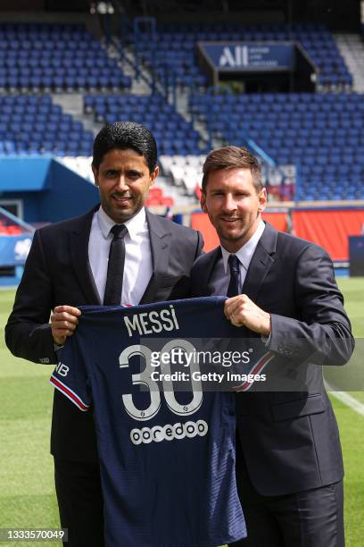 Lionel Messi poses with his jersey next to President Nasser Al Khelaifi after the press conference of Paris Saint-Germain at Parc des Princes on...