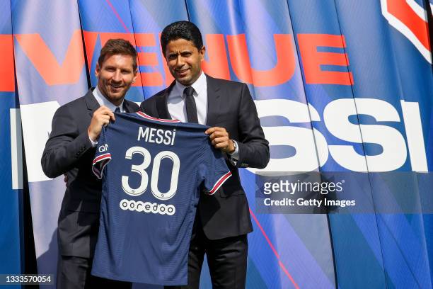 Lionel Messi poses with his jersey next to President Nasser Al Khelaifi after the press conference of Paris Saint-Germain at Parc des Princes on...