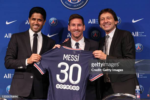 Lionel Messi poses with his jersey next to President Nasser Al Khelaifi and Leonardo after the press conference of Paris Saint-Germain at Parc des...