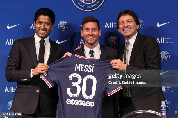 Lionel Messi poses with his jersey next to President Nasser Al Khelaifi and Leonardo after the press conference of Paris Saint-Germain at Parc des...