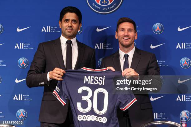 Lionel Messi poses with his jersey next to President Nasser Al Khelaifi after the press conference of Paris Saint-Germain at Parc des Princes on...