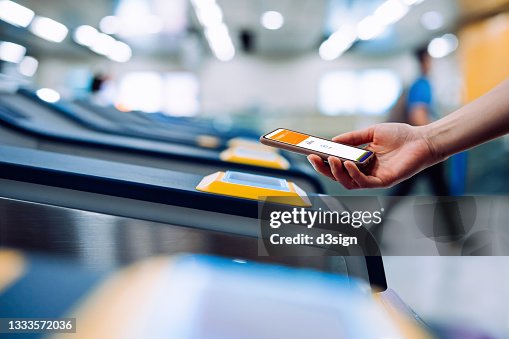 Cropped shot of young Asian woman checking in at subway station, making a quick and easy contactless payment for subway ticket via smartphone. NFC technology, tap and go concept Cropped shot of young Asian woman checking in at subway station, making a quick and easy contactless payment for subway ticket via smartphone. NFC technology, tap and go concept