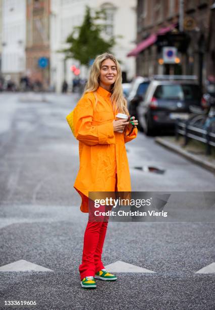 Emili Sindlev seen wearing orange jacket, red pants outside The Garment on August 10, 2021 in Copenhagen, Denmark.