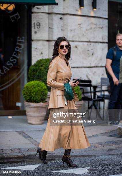 Guest is seen wearing beige skirt, blazer, green Bottega Veneta bag outside The Garment on August 10, 2021 in Copenhagen, Denmark.