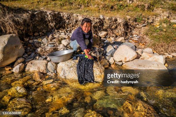 tibetan girl washing clothes in the river, upper mustang - asia village river bildbanksfoton och bilder