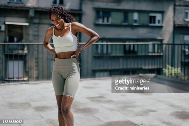 entrenamiento callejero: mujer afroamericana haciendo ejercicio en la azotea - leggings fotografías e imágenes de stock