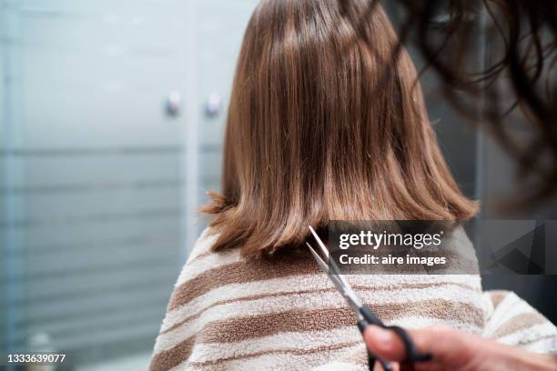 people cutting hair using a scissors child backwards with brown short straight hair wearing a bath towel indoors domestic bathroom - girl short hair stock pictures, royalty-free photos & images