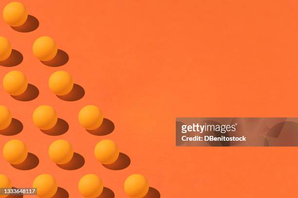 pattern of orange ping pong balls with hard shadow on the left side, with copy space on the right. on orange background. group, design and futuristic concept - group 1 stockfoto's en -beelden