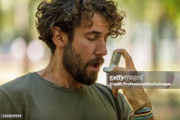 handsome man has problems with the respiratory system so he uses an inhaler. - inhalation stock pictures, royalty-free photos & images