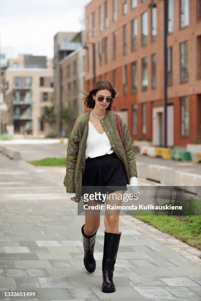 Jacqueline Zelwis wearing black shorts, white top, army green jacket and long boots outside Designer Remix during Copenhagen fashion week SS22 on...