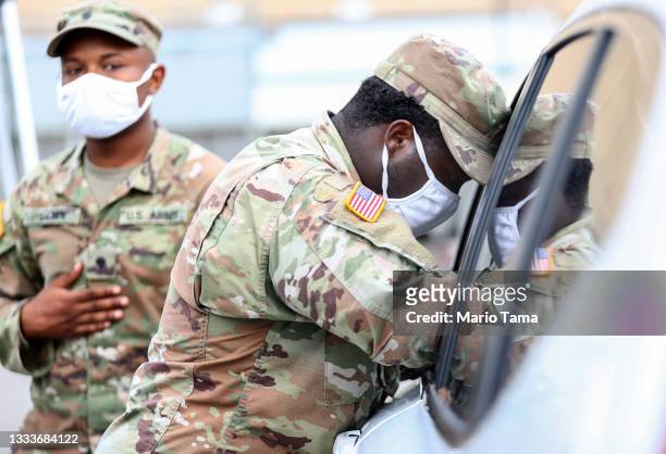 Louisiana Army National Guard soldier Raymond Hill assists a driver to register at a COVID-19 drive-through testing site operated by the National...