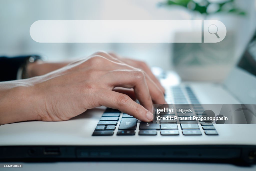 Hand typing on laptop keyboard for searching information in search engine toolbox