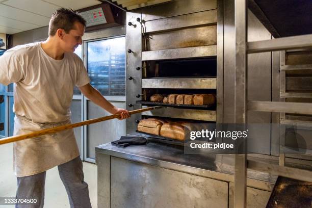 baker taking bread out of oven - bread bildbanksfoton och bilder