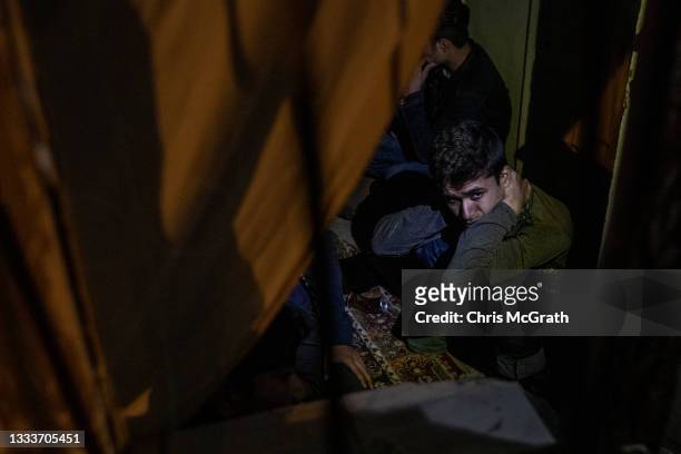 Migrants from Afghanistan and Pakistan wait to be escorted out of a smuggler's safe house after a raid by police from Turkey's anti-smuggling...