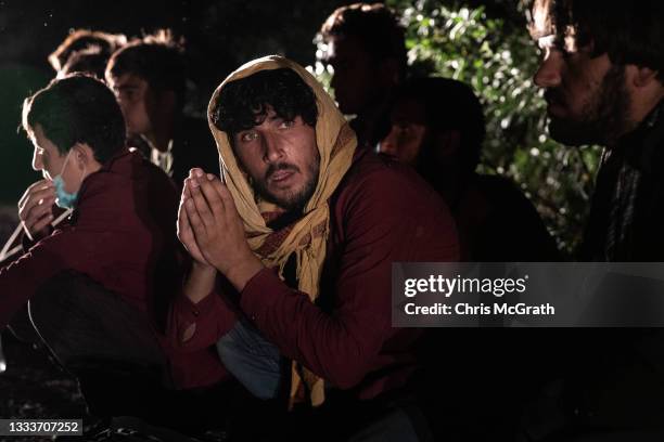 Afghan migrants, some with injuries, sit on the roadside after the van they were being transported in was ditched into a tree as the smuggler driving...