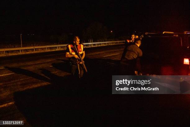 Afghan migrants, some with injuries, sit on the roadside after the van they were being transported in was ditched into a tree as the smuggler driving...