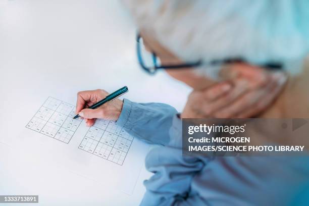 senior woman solving sudoku puzzle - dementia stock-fotos und bilder