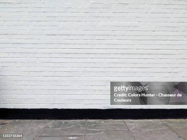 painted brick wall and weathered sidewalk in london - wand stock-fotos und bilder