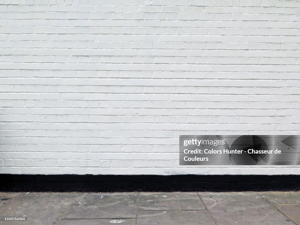 Painted brick wall and weathered sidewalk in London