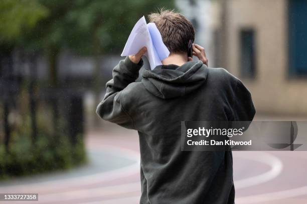 Student speaks on the phone after opening their GCSE results at the City of London Academy on August 12, 2021 in London, England. Year 11 students...
