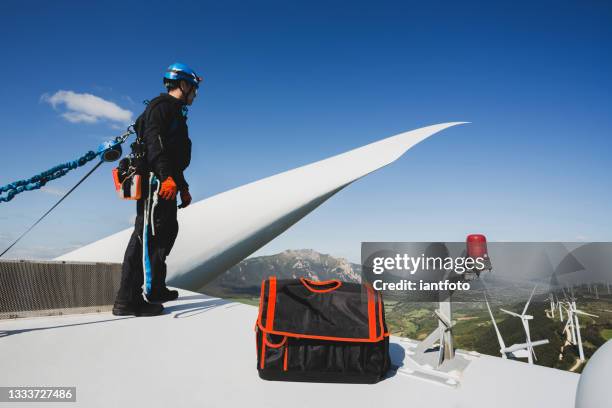 ingenieur, der an der spitze einer windkraftanlage arbeitet. - sicherheitsgurt sicherheitsausrüstung stock-fotos und bilder