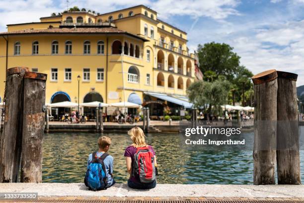 mother and son sitting in the harbour of riva del garda and enjoying view of the town and the lake. - riva del garda stock pictures, royalty-free photos & images