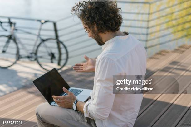frustrated young businessman sitting on the stair and trying to fix his laptop - out of service stock pictures, royalty-free photos & images