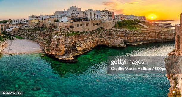 scenic view of sea by buildings against sky during sunset,polignano a mare,bari,italy - as bari foto e immagini stock