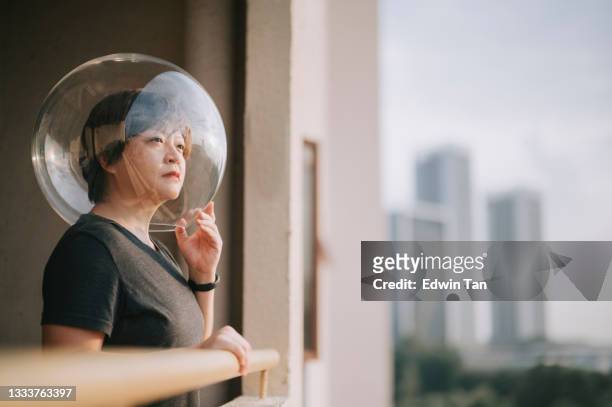 creative portrait side view asian chinese mid adult woman with transparent full helmet looking at a view from balcony - helmet visor stock pictures, royalty-free photos & images