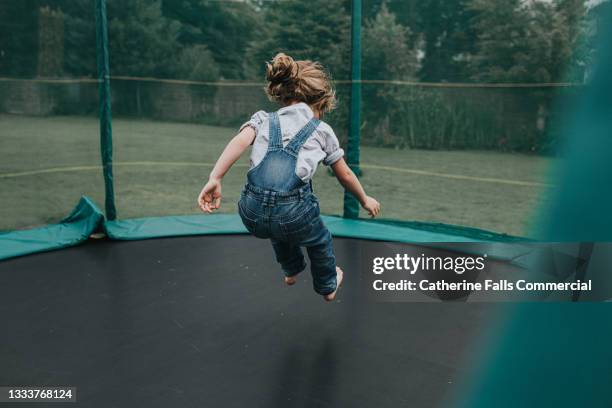 a child bounces on a large trampoline outside - kids gymnastics stock-fotos und bilder