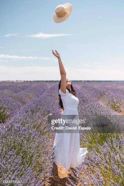 young woman throwing hat in air in field - throwing flowers stock pictures, royalty-free photos & images